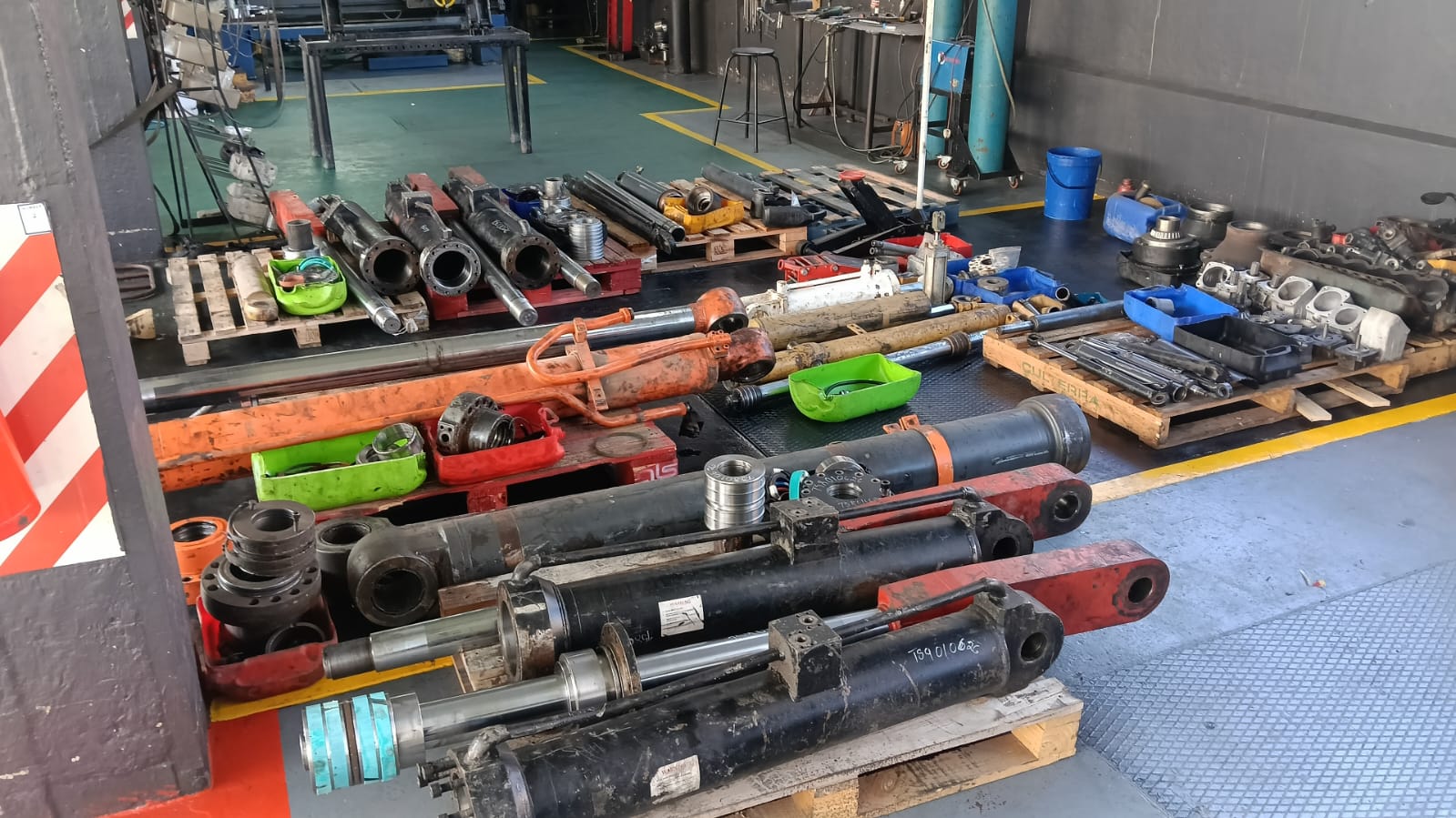 Worn hydraulic cylinders, shafts and pistons on pallets waiting to be stripped